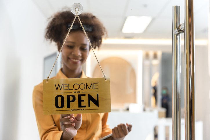 A business sign that word ‘Open’ on cafe or restaurant hang on door at entrance. Small business owner turning the sign for the reopening iStock